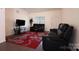 Inviting living room with plush black seating, a vibrant red rug, and a modern entertainment center at 6919 Ware Rd, Charlotte, NC 28212