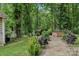 Lush backyard with a stone walkway, a shed, a brick fire pit and mature trees at 719 Dawn Cir, Charlotte, NC 28213