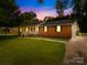 Charming brick home at dusk features an attached garage and a lush green lawn at 815 Lakeside Cir, Lancaster, SC 29720