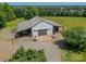 Aerial view of large garage building with roll up doors in a rural location, surrounded by green grass and trees at 8698 Rocky River Rd, Harrisburg, NC 28075