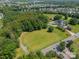 Expansive aerial view showcasing a home, pool, barn, and surrounding land with mature trees and neighborhood beyond at 8698 Rocky River Rd, Harrisburg, NC 28075