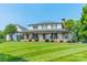 Attractive two-story home featuring a covered front porch with rocking chairs and lush green lawn at 8698 Rocky River Rd, Harrisburg, NC 28075