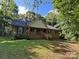 Charming brick home with a covered front porch and lush, mature trees in a well-manicured yard at 8819 Noah Helms Rd, Indian Trail, NC 28079