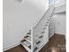 Elegant staircase featuring dark hardwood floors, white risers, and a classic white railing leading to the upper level at 919 Cityscape Dr, Charlotte, NC 28205