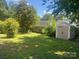Spacious backyard with green grass, mature trees, a fence, and a storage shed at 9612 Farmridge Ln, Matthews, NC 28105