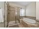 Bathroom with glass shower and soaking tub with tile surround and decorative border and white blinds at 1329 Jacemans Way, Cornelius, NC 28031