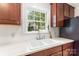 Close-up of a kitchen sink with white countertops and dark wood cabinetry beneath a sunny window at 1400 Matheson Ave, Charlotte, NC 28205