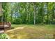 A view of the backyard, highlighting the lush, green lawn, mature trees, and wooden deck with stairs at 144 Stoneybrook Rd, Salisbury, NC 28147