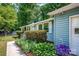 Close up of the side of a light blue house with white trim, lush green bushes, and vibrant purple flowers at 144 Stoneybrook Rd, Salisbury, NC 28147