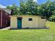 Exterior of a yellow outbuilding with a green door and simple window in a yard with mature trees at 1585 Salem Church Rd, Lincolnton, NC 28092