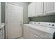 Practical laundry room with white washer and dryer, storage cabinets, and a white painted door at 1974 Links View Dr, Fort Mill, SC 29707