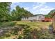 The large backyard showcases the home's exterior, complemented by green grass, trees, and a charming deck, ideal for outdoor enjoyment at 3585 Woodstream Dr, Maiden, NC 28650