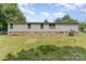 The back of the house features a stone foundation, with a lush lawn leading up to the siding and windows at 3585 Woodstream Dr, Maiden, NC 28650