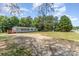 Wide angle view of the home featuring a gravel driveway with spacious yard and mature trees surrounding the property at 3585 Woodstream Dr, Maiden, NC 28650