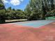 Well-maintained tennis court surrounded by lush trees offering a shady sports experience at 4240 Ladys Slipper Ln, Matthews, NC 28105