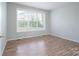 Bright bedroom featuring wood floors, neutral paint, large windows, and a view of the neighborhood at 4392 Sunset Rose Dr, Fort Mill, SC 29708