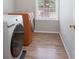 Modern laundry room is equipped with new washer and dryer, wood floors, and a window at 4392 Sunset Rose Dr, Fort Mill, SC 29708