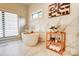 A soaking tub sits beneath a window and next to a wooden shelf in this bright and airy bathroom at 445 Sundown Rd, Mooresville, NC 28117