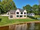 Beautiful two-story home with large windows, a covered deck, and a sprawling green lawn by the lake at 445 Sundown Rd, Mooresville, NC 28117