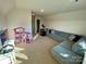 Spacious bonus room with a large sectional sofa, TV, dollhouse, and neutral carpeting at 5005 Blue Serenity Ct, Denver, NC 28037