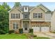 Charming two-story home with a stone facade, symmetrical windows, and an attached two-car garage at 5021 Meadow Woods Dr, Lowell, NC 28098