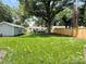 Expansive backyard with lush lawn, mature trees, wooden fence, and charming deck at 5033 Baylor Dr, Charlotte, NC 28210