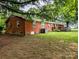 Brick home with a patio and green grass in a spacious backyard, surrounded by trees at 5628 White Store Rd, Wingate, NC 28174