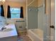 Retro bathroom features light blue tiles, a shower-tub combo, a sink, and a window at 5628 White Store Rd, Wingate, NC 28174