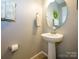 Stylish half-bathroom with a pedestal sink, elegant mirror, and neutral color palette for a modern look at 54 Woodsdale Se Pl, Concord, NC 28025