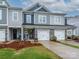 Charming townhome featuring a stone facade, two-car garage, landscaped yard, and inviting curb appeal at 54 Woodsdale Se Pl, Concord, NC 28025