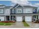 A modern townhome with a two-car garage, stone accents, and nicely landscaped front yard at 54 Woodsdale Se Pl, Concord, NC 28025