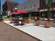 Inviting outdoor seating area with red umbrellas and lush landscaping, perfect for dining al fresco at 54 Woodsdale Se Pl, Concord, NC 28025