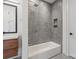 The bathroom features a tub shower with gray modern tile, a shower niche and a wood vanity at 5930 Midsomer Rd, Charlotte, NC 28214