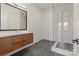 Modern bathroom featuring a walk-in glass shower, dark flooring, and a floating vanity with a large mirror at 5930 Midsomer Rd, Charlotte, NC 28214