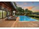 Backyard view of a modern in-ground pool surrounded by a wooden deck and lounge chairs at 5930 Midsomer Rd, Charlotte, NC 28214