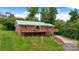 Charming brick home with a green roof, wooden deck, and lush green lawn at 6294 Southlake Dr, Hickory, NC 28601