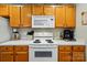 A full kitchen with wooden cabinets, a white microwave, an oven, and a coffee maker at 7671 Bluff Point Ln, Denver, NC 28037