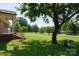 Expansive front yard with lush greenery, mature trees, and a charming brick home's corner visible at 7869 Cherry Point Dr, Denver, NC 28037