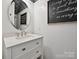 Chic bathroom features a round mirror, white wainscoting, and modern vanity with a light countertop at 9405 Gladden Hill Ln, Pineville, NC 28134