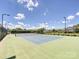 Well-maintained tennis court on a sunny day, surrounded by fencing and mature trees at 9405 Gladden Hill Ln, Pineville, NC 28134