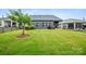 A spacious backyard view of the property featuring green grass, trees, and the back of the home at 9525 Festival Way, Charlotte, NC 28215