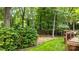 A serene backyard features a lush lawn, privacy hedge, and a wooden deck overlooking a wooded area at 9901 Pallisers Ter, Charlotte, NC 28210