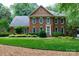 Traditional two-story brick home featuring a manicured front lawn and mature landscaping at 9901 Pallisers Ter, Charlotte, NC 28210
