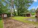 The backyard features a driveway leading to sheds, mature trees and ample green space at 1008 Midway Dr, Gastonia, NC 28054