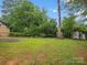 Overgrown backyard with shed, mature trees, and a grassy area at 1008 Midway Dr, Gastonia, NC 28054