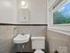 Neutral-toned bathroom with a pedestal sink and toilet beneath a modern mirror at 1008 Midway Dr, Gastonia, NC 28054