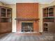 Close-up of brick fireplace with wooden mantle and decorative fireplace tools at 1008 Midway Dr, Gastonia, NC 28054