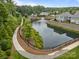 Scenic aerial view of pond and fountain, with lush landscaping and walkway along the water at 17112 Courtside Landing Dr, Cornelius, NC 28031