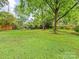 Expansive backyard featuring lush green grass and mature trees offering serene outdoor space at 1723 Woodland Dr, Charlotte, NC 28205