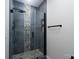 Sleek glass-enclosed shower boasting dark tile and pebbled flooring at 304 Cabarrus W Ave, Concord, NC 28025